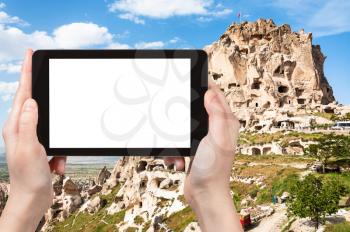 travel concept - tourist photographs of rock-cut Uchisar castle in Cappadocia in spring in Turkey on smartphone with empty cutout screen with blank place for advertising