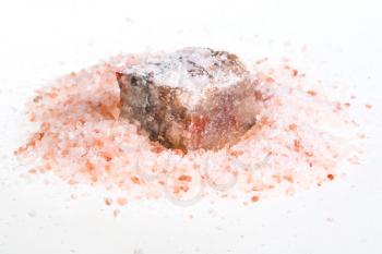 natural Halite mineral in pile of grained pink Himalayan Salt on white background