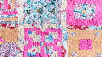 textile background - square pattern of patchwork scarf stitched from various silk strips and crushed pink cotton fabric