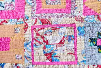 textile background - ornamental patchwork scarf stitched from various silk strips and crushed pink cotton fabric