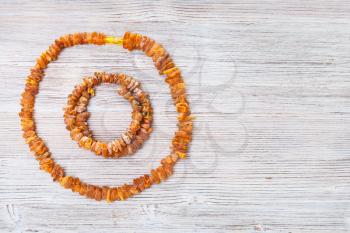 top view of rough amber necklace and bracelet on gray wooden board with copyspace