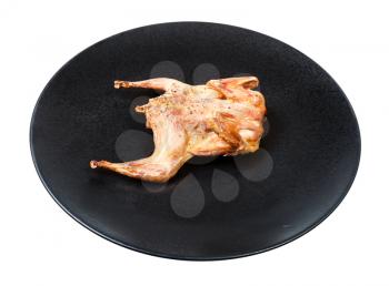 roasted whole flattened quail on black plate isolated on white background