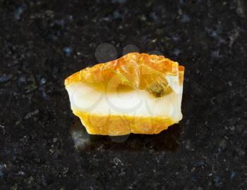 closeup of sample of natural mineral from geological collection - unpolished yellow Amber gemstone on black granite background from Baltic Sea, Kaliningrad, Russia