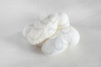 natural silkworm cocoons for facial skin care on white silk fabric closeup