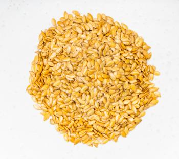 top view of pile of golden flax seeds close up on gray ceramic plate