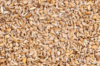 food background - uncooked crushed Emmer farro hulled wheat groats