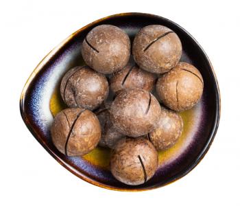 top view of sawn macadamia nuts in ceramic bowl isolated on white background