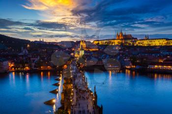 Aerial view of illuminated Prague castle and Charles Bridge with tourist crowd over Vltava river in Prague, Czech Republic. Prague, Czech Republic in the evening