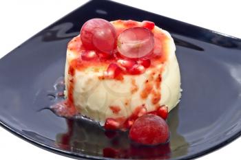 Sweet dessert with fresh grapes berries and pomegranate grains on black plate.