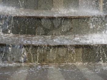 The stream of water on the gray granite steps.