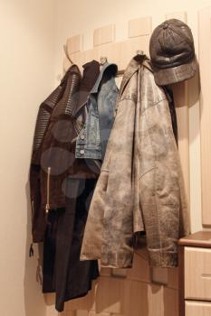 Various clothes hanging on a wooden coat rack.