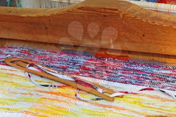 Multicolored rug on a weaving loom taken closeup.