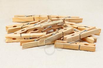Wooden clothespins heap taken on white fabric background.