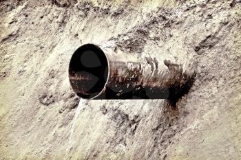 Rusty water drain pipe on slope taken closeup. Monochrome image.