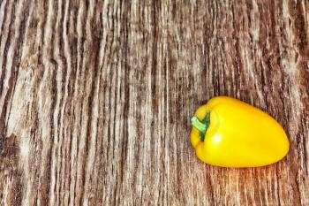 Single yellow sweet pepper on grunge wooden background taken closeup.Toned image.