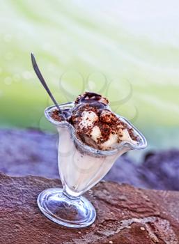 Vanilla Ice cream topped with chocolate syrup on blurry sea wave background taken closeup.Toned image.