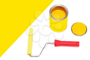 Bank of yellow paint and roller paintbrush on white background with empty space for text.