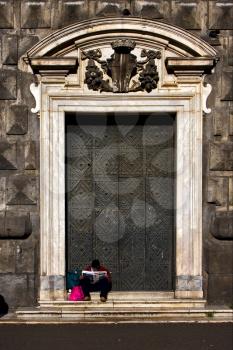 the brown gate  in the church gesu nuovo in naples and a homeless reading a newspaper
