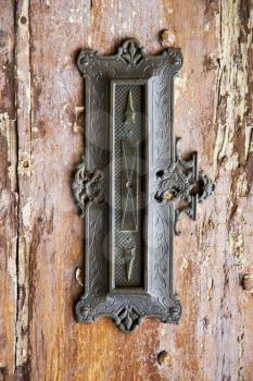 post mail abstract   rusty brass brown knocker in a  door curch  closed wood lombardy italy  varese azzate
