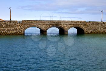 atlantic ocean lanzarote  bridge and street lamp in the blue sky   arrecife teguise spain
