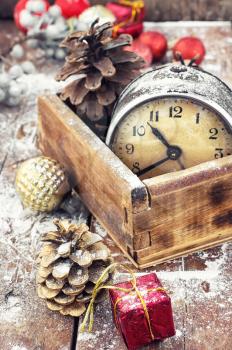 outdated watch in wooden box on the background of Christmas decorations and pine cones.Photo tinted.