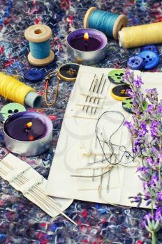 buttons and thread on background of cut branches of lavender.