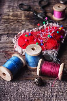 pin cushion with needles,thread and buttons for sewing on stylish wooden background
