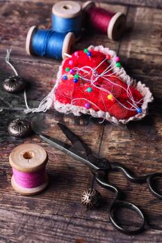 pin cushion with needles,thread and buttons for sewing on stylish wooden background