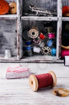 Wooden spool of red thread on the background of sewing tools.Selective focus