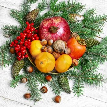 tangerines,pomegranates,persimmons and nuts,decorated with fir branches