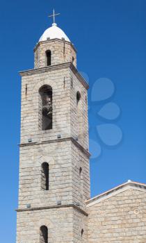 Bell tower of Propriano church, gray stone facade on a blue sky background