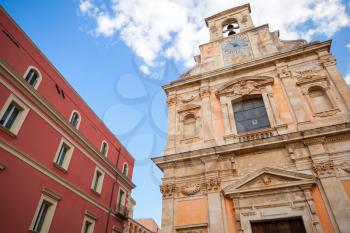Church with wall clock and old red house facade, Gaeta, Italy