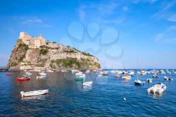 Coastal landscape of Ischia port with Aragonese Castle and small wooden boats