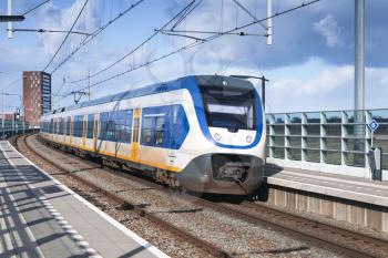 Passenger electric train goes near railway platform in Amsterdam, Netherlands