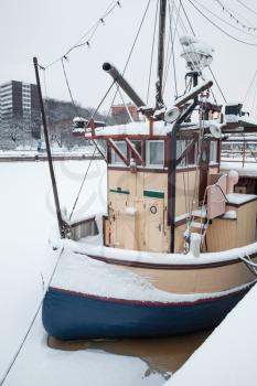 Small boat moored near river coast. Winter in Turku town, Finland