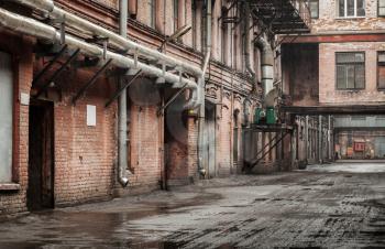 Old industrial street view with red brick facades and tubes