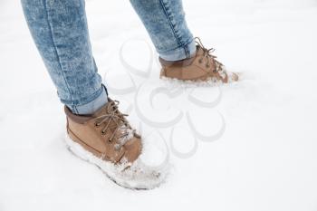 Girl feet in blue jeans and high boots of nubuck standing in fresh snow, winter walking