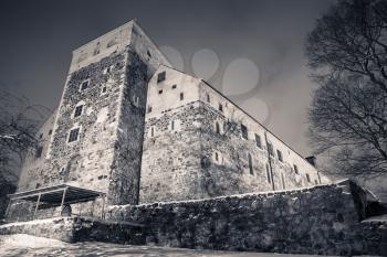 Monochrome photo of Turku Castle at night, it is a medieval building in the city of Turku in Finland. It was founded in the late 13th century and stands on the banks of the Aura River