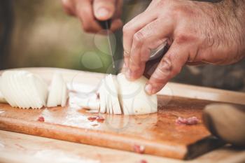 Slicing of a white onion. Cook hands with knife, close-up photo with soft selective focus