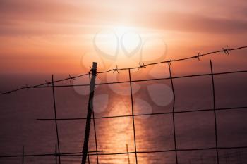 Barbed wire fence with sunset over sea on a background. Landscape of Greek island Zakynthos