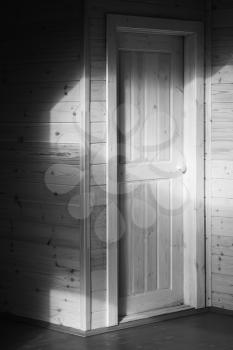 White door. Empty wooden house interior. Black and white vertical photo