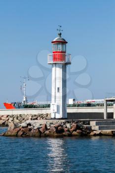 White lighthouse tower with red top stands on the entrance breakwater in port of Burgas, Black Sea coast, Bulgaria