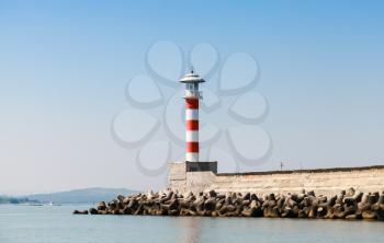 Striped red and white lighthouse tower stands on the entrance pier in port of Burgas, Black Sea coast, Bulgaria
