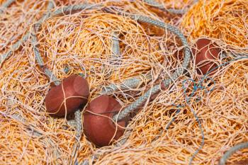 Yellow fishing net with red floats lays in port. Close-up background photo with selective focus
