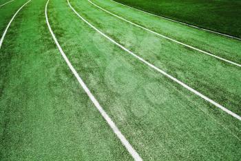 Empty running track with artificial turf and white lines