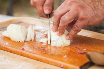 Onion slicing. Cook hands with knife, close-up photo, selective focus