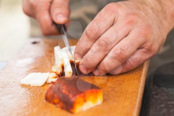 Smoked lard slicing. Cook hands with knife, close-up photo, selective focus