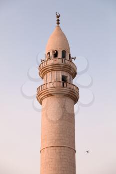 Minaret of Mosque in Aqaba city, Hashemite Kingdom of Jordan. Vertical photo over light blue sky
