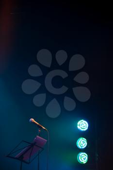 Empty music stage, vertical background photo with microphone and blurred blue green LED lights 