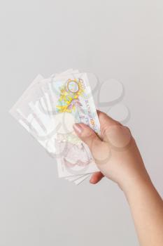 Ten pound notes of the Bank of England in female hand. Close-up photo over gray background with selective focus